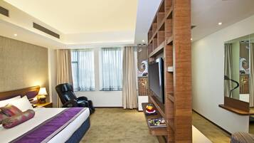 A hotel room with a bed, a TV, a chair, a desk, and a mirror.