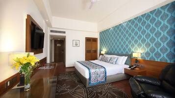 Habitación de hotel con cama, escritorio, silla, televisor y pared con diseño.