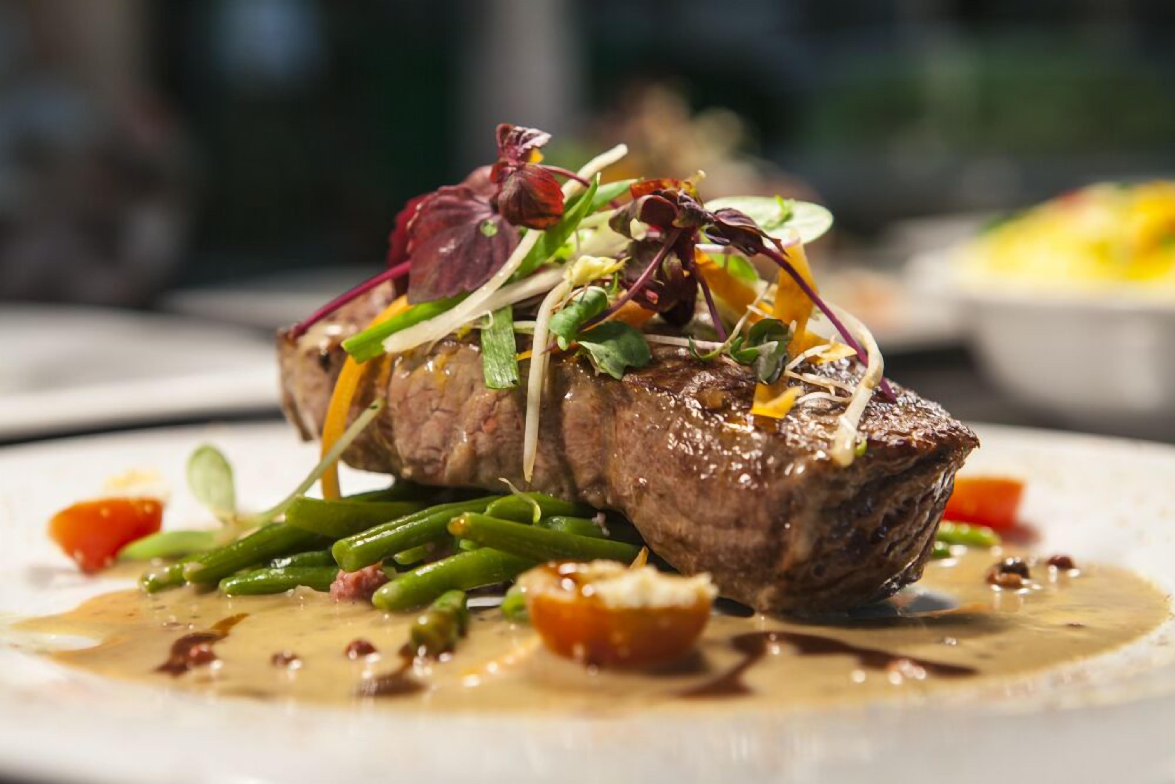 Un plato con bistec, judías verdes y salsa cremosa.