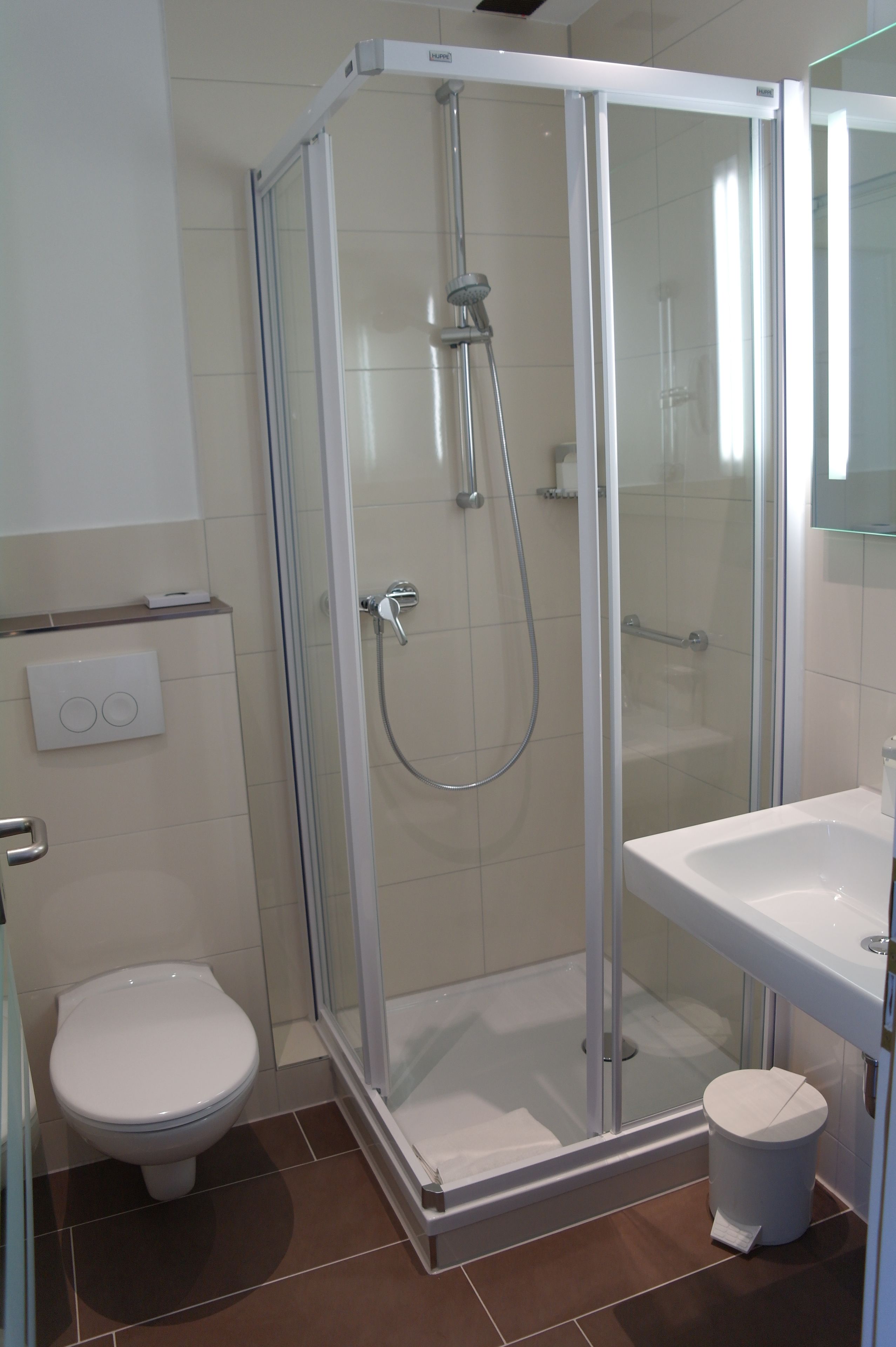 A modern bathroom with a glass-enclosed shower, a toilet, and a sink.