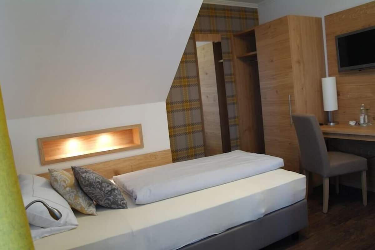 Ein Schlafzimmer mit Bett, Schreibtisch, Stuhl, Fernseher und Kleiderschrank.