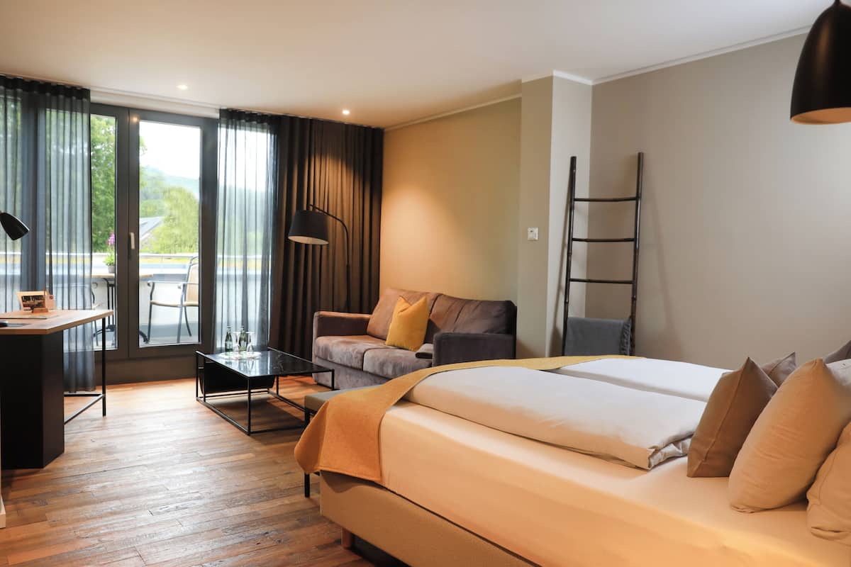 Ein modernes Hotelzimmer mit einem großen Bett, einem Schreibtisch, einer Sitzecke und einem Essbereich.