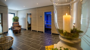 Un hall d’hôtel moderne avec une grande bougie, un panier en osier et un fauteuil en cuir.