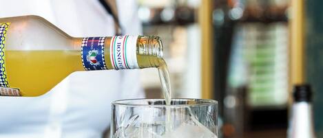 A bartender pouring a yellowish drink into a clear glass with a diamond pattern.