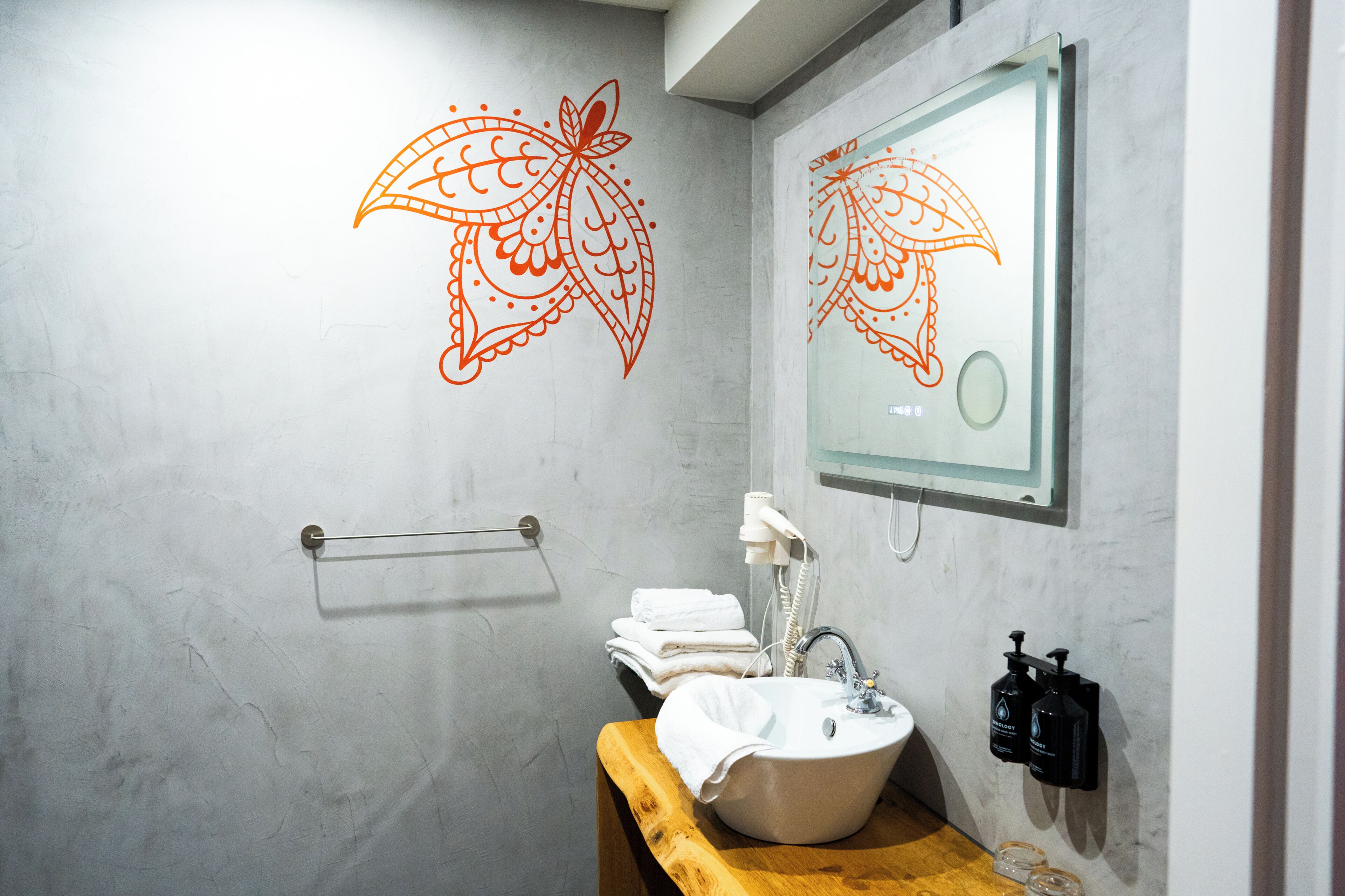 Een badkamer met een wastafel, spiegel, handdoekhouder en decoratieve wandkunst.