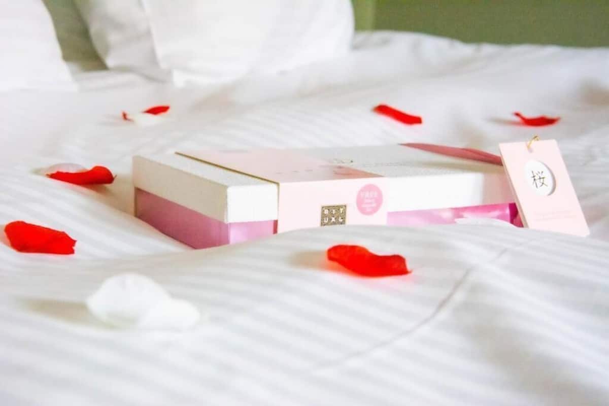 A bed with a pink and white box and a tag on it.
