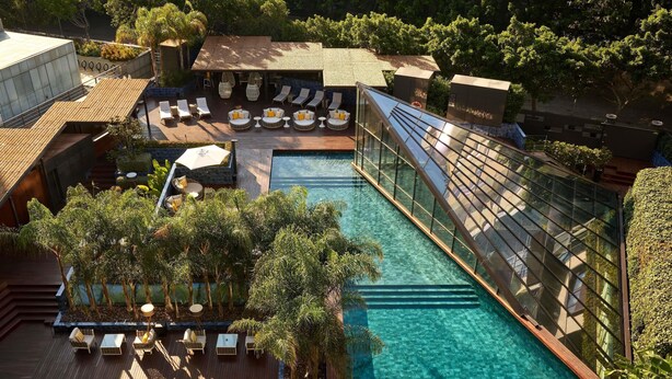 Un área de piscina en la azotea con sillones de descanso y un puente de cristal.
