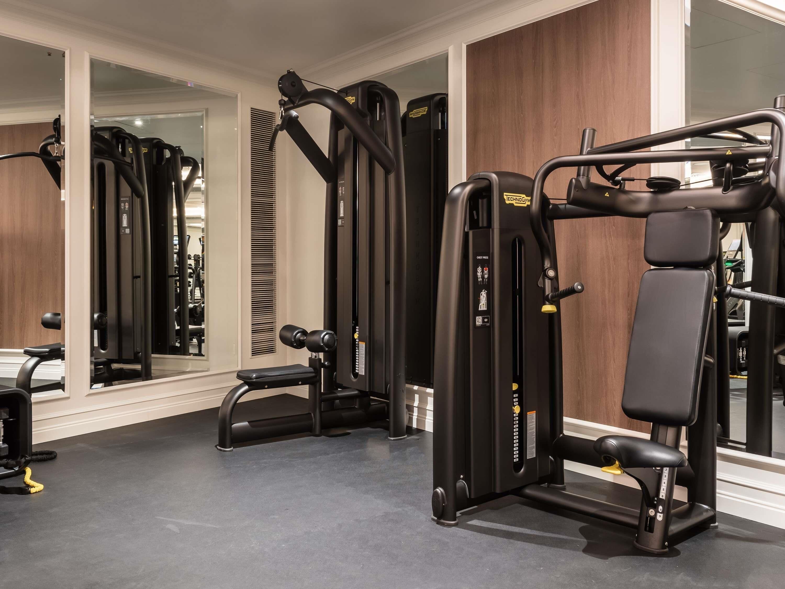 A gym with exercise equipment, a mirror, and a wooden wall.