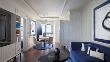 A modern living room with a blue sofa, a coffee table, and a dining area with a white table and chairs.