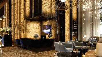 A modern lobby with a reception desk, seating area, and a large screen.