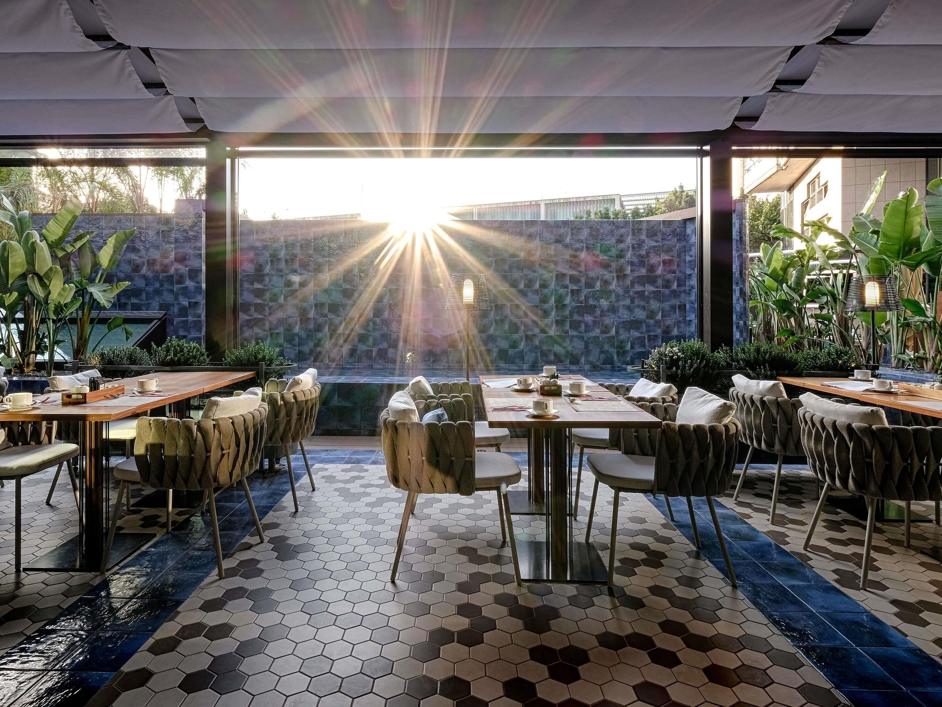Ein Restaurant mit sechseckig gefliestem Boden, Tischen mit Stühlen und großen Fenstern für natürliches Licht.