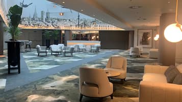 Un lobby espacioso con vista a la ciudad, muebles modernos y una planta grande en maceta.