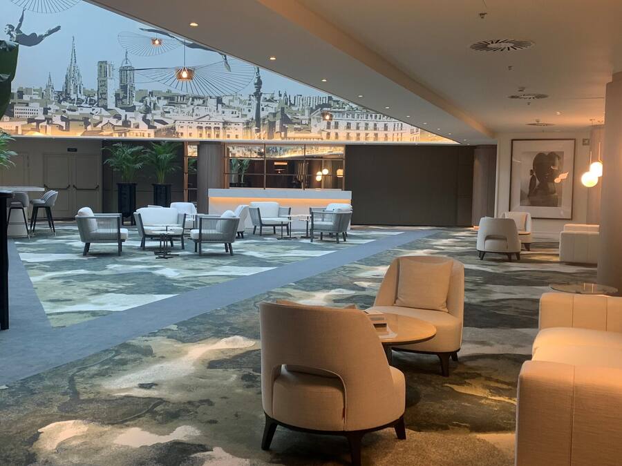 Un lobby espacioso con vista a la ciudad, muebles modernos y una planta grande en maceta.