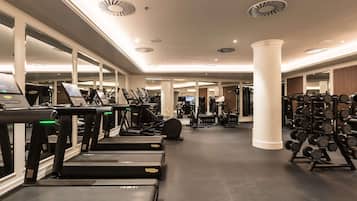 Un gimnasio con cintas de correr, máquinas de pesas y espejos.