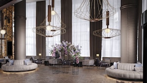 A modern lobby with a circular seating area, large windows with curtains, and unique geometric pendant lighting. - Sofitel Barcelona Skipper (Barcelona)