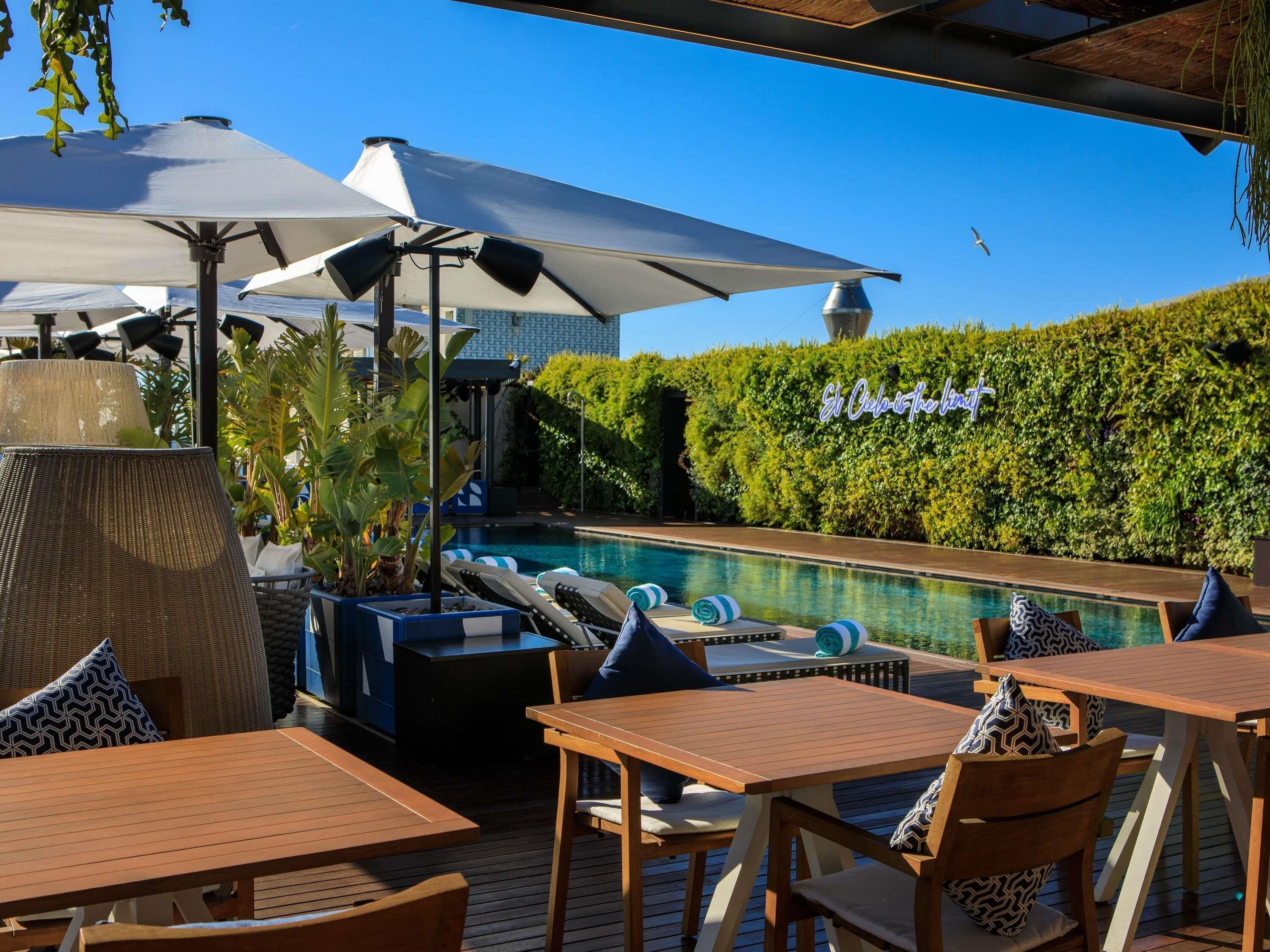 Un espace aménagé au bord de la piscine, avec des chaises longues, des parasols et une piscine.
