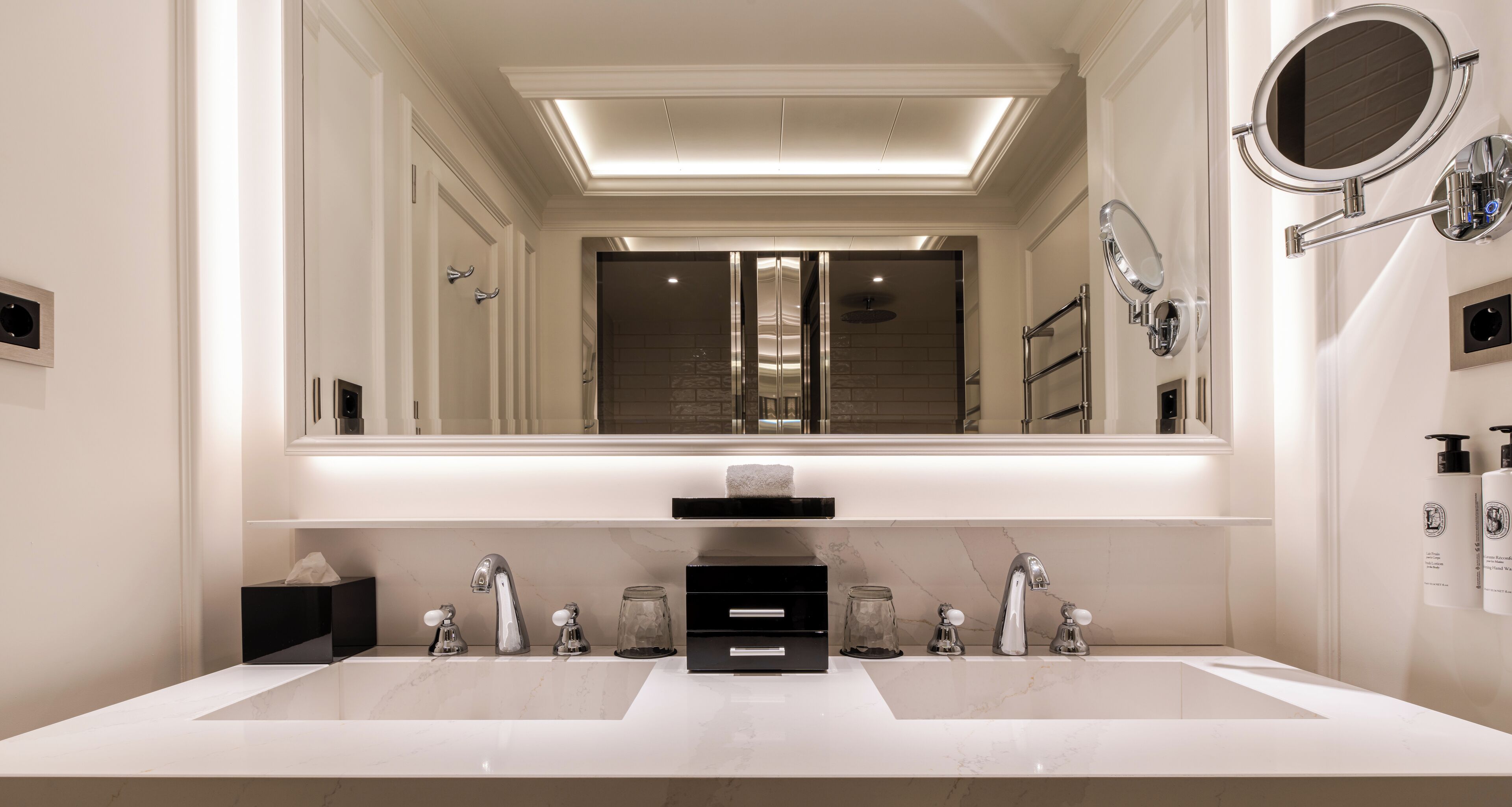 Un baño moderno con un espejo grande, dos lavamanos y una zona de ducha.