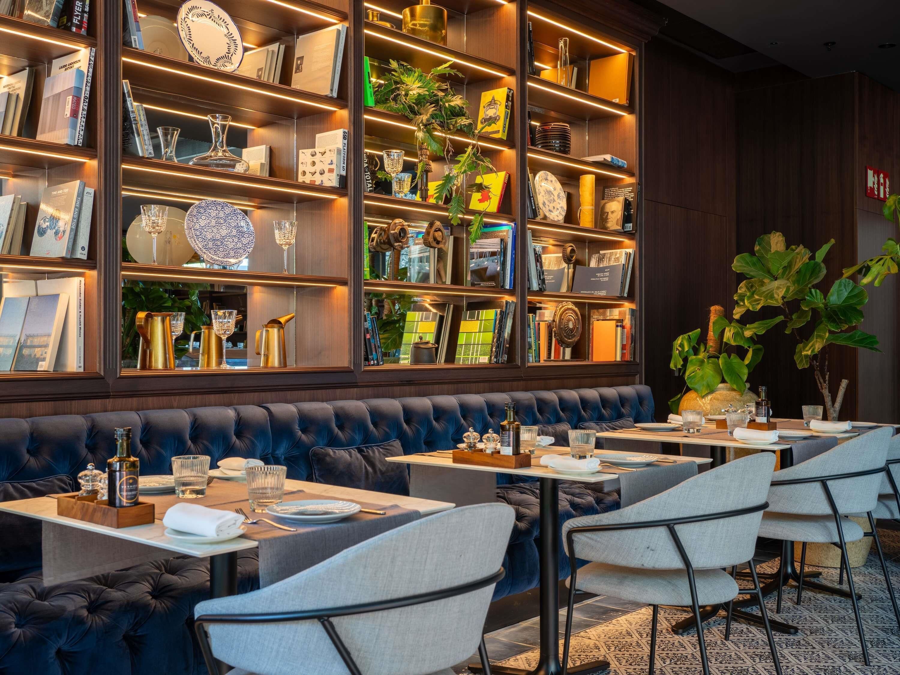 Un restaurante con interior de madera oscura, un banco tapizado en azul y una variedad de platos y libros en estanterías.