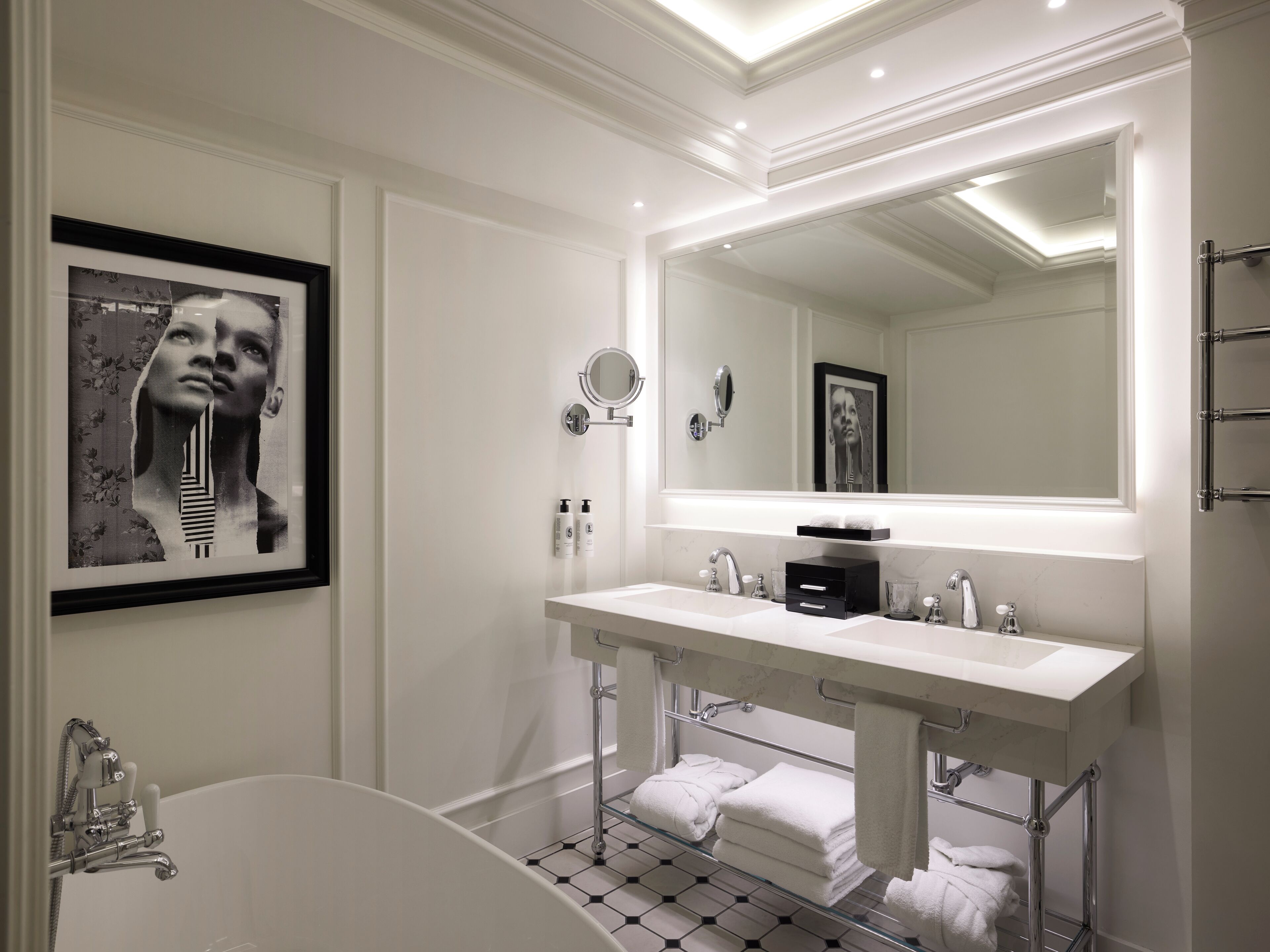 A modern bathroom with a double sink vanity, a large mirror, and a bathtub.