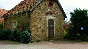 Un edificio de piedra con techo de tejas, puerta de madera y una ventana pequeña.