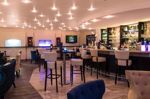 A bar area with multiple seating options, a television mounted on the wall, and a well-stocked bar counter.