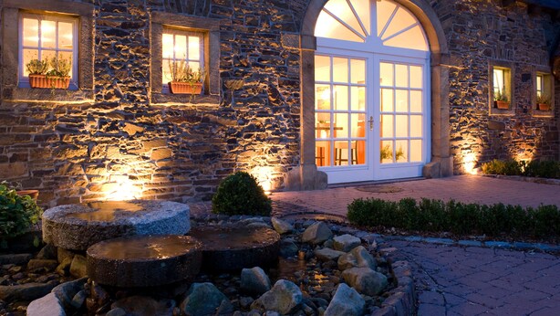 A stone building with a large arched doorway and windows with potted plants.