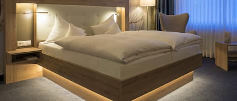 Une chambre d’hôtel moderne avec un grand lit, des tables de chevet, une petite table et une lampe.