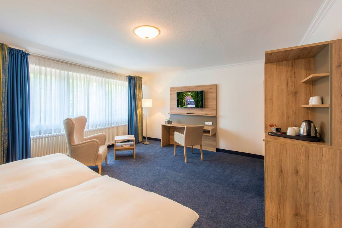 Une chambre d’hôtel avec un grand lit, un bureau, une chaise, une télévision et une armoire.