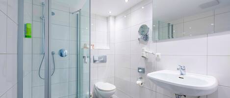A modern bathroom with a glass-enclosed shower, a toilet, and a sink with a mirror above it.