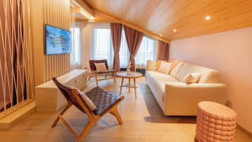 A modern living room with a sofa, chairs, a coffee table, and a TV mounted on the wall.