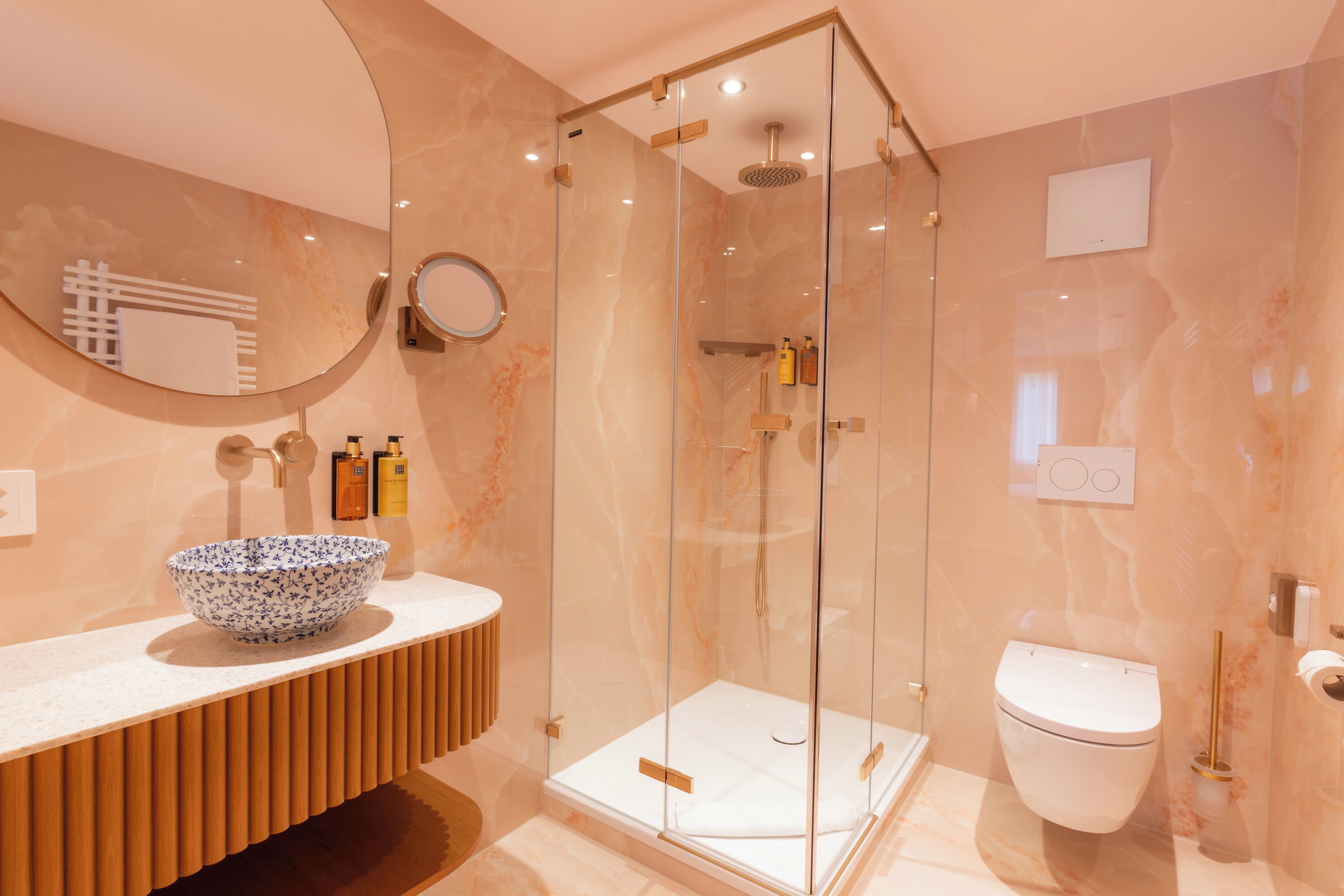 A modern bathroom with a glass-enclosed shower, a white toilet, and a marble vanity with a bowl sink.