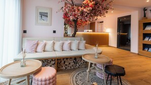 Una habitación acogedora con un sofá, una mesa redonda de madera y un árbol artificial grande.