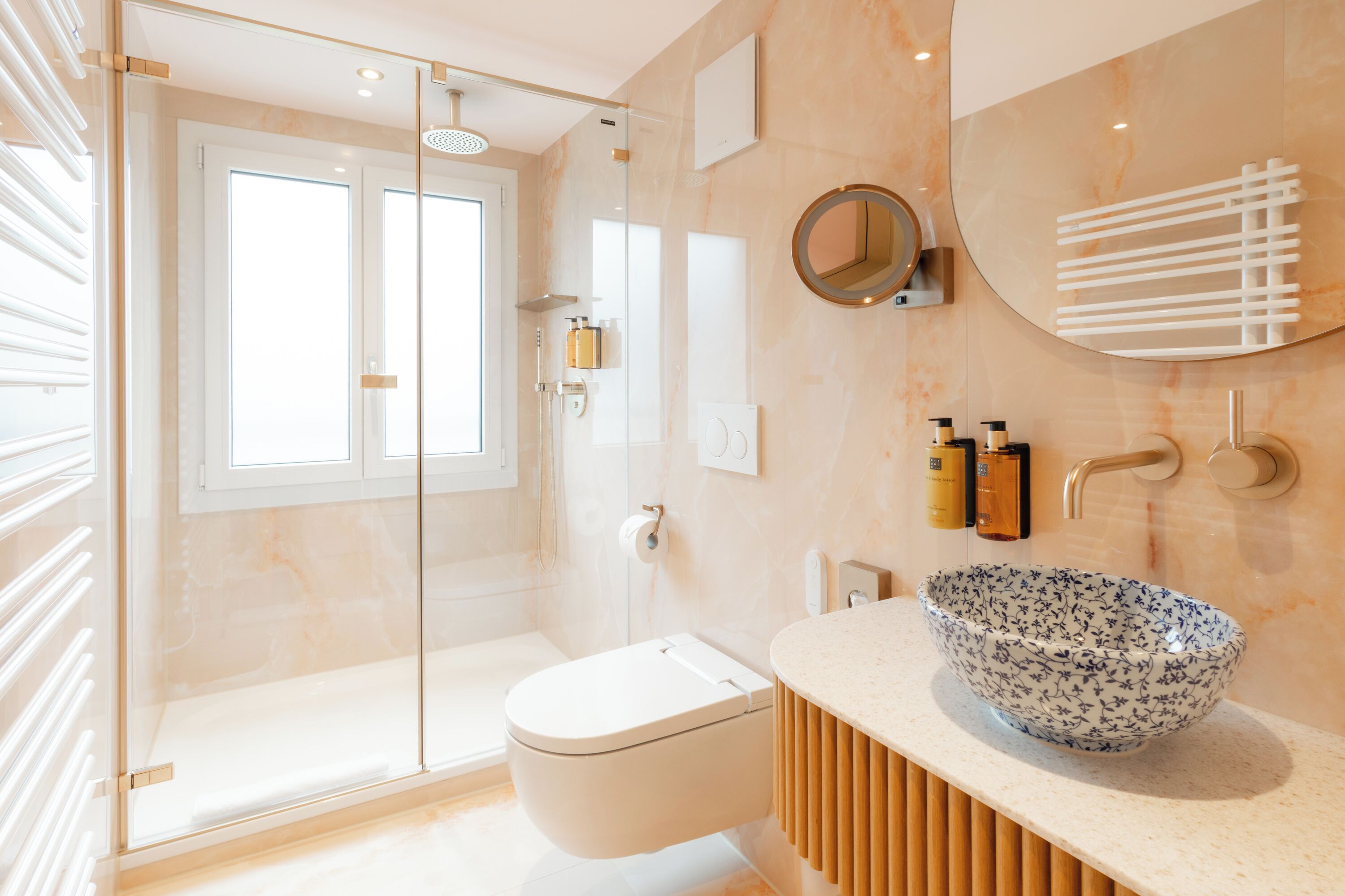 Un baño moderno con ducha envuelta en vidrio, inodoro, tocador con lavabo y espejo.