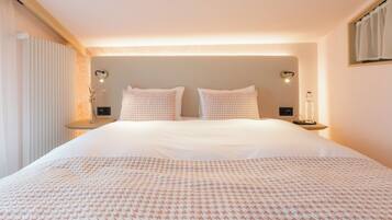 A large bed with a patterned bedspread, two bedside tables with lamps, and a wall-mounted light fixture.