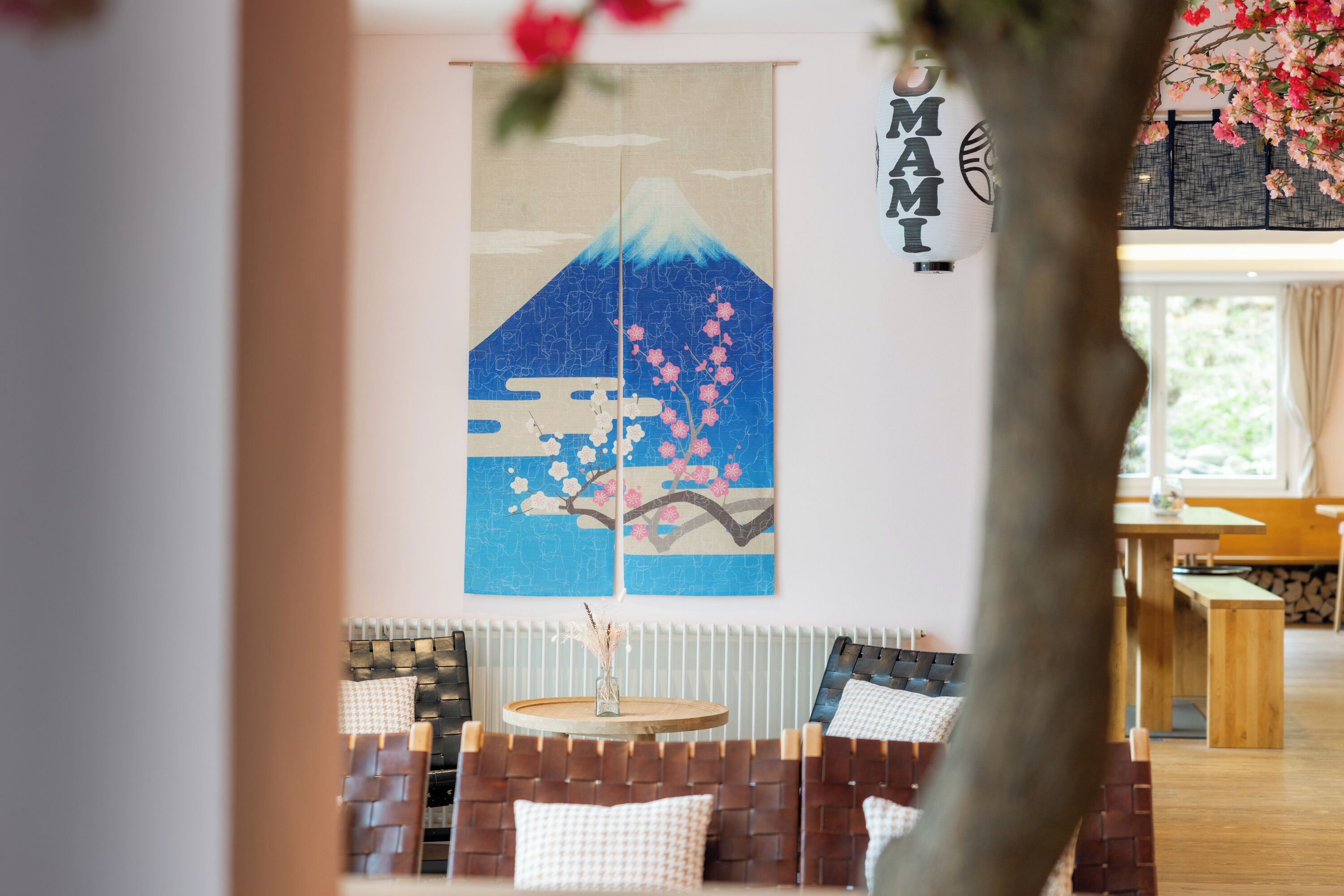 Een traditionele Japanse kamer met tatami vloerbedekking, een lage tafel en een wandkunstwerk waarop de berg Fuji en kersenbloesems afgebeeld zijn.