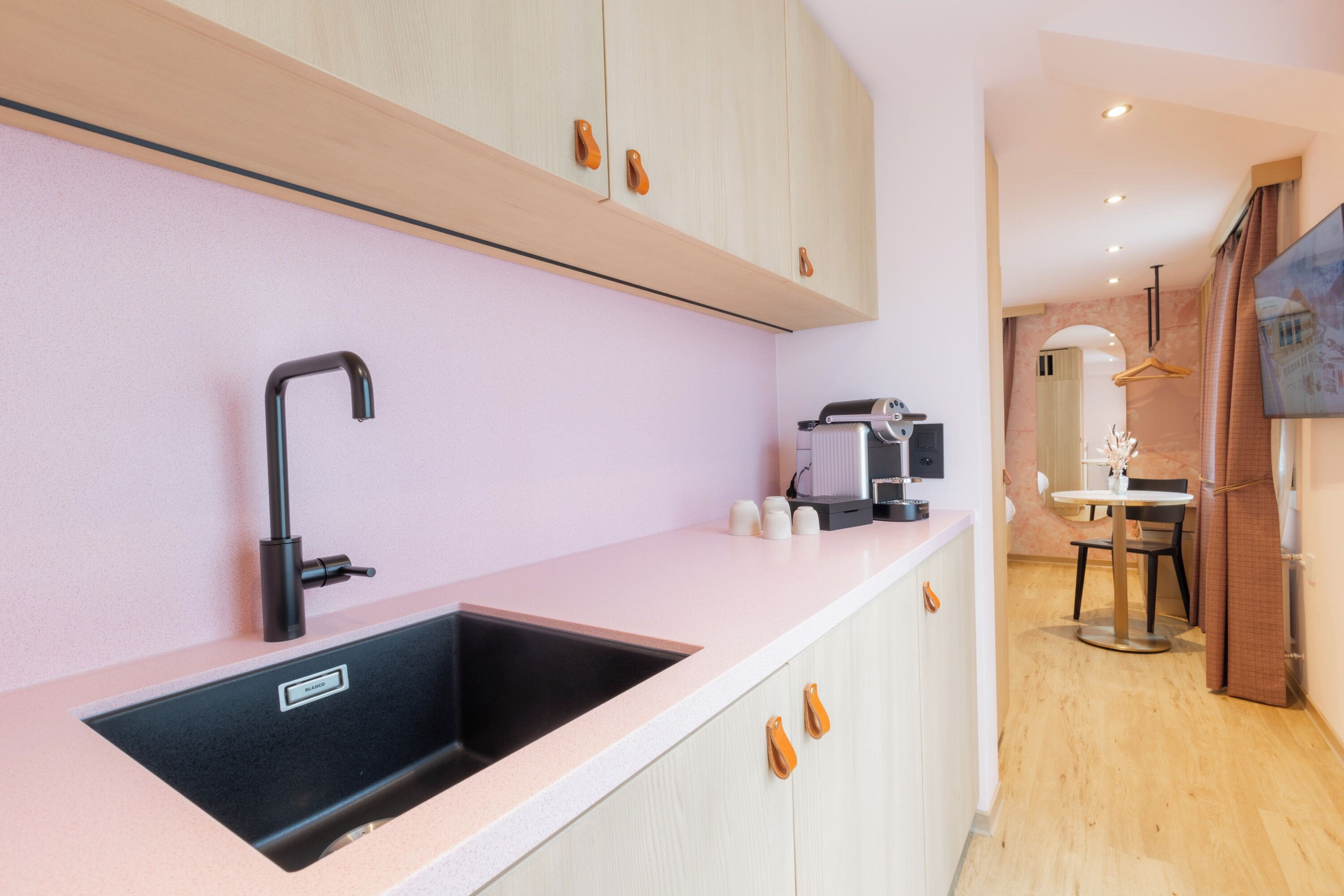 A modern kitchen with a sink, cabinets, and a coffee machine.