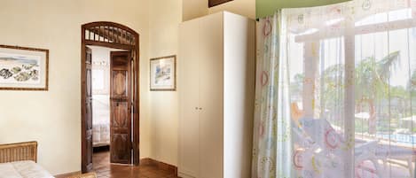 Ein Zimmer mit einem Bett, einem Kleiderschrank und einer Tür zu einem anderen Raum.