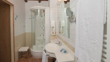 A bathroom with a glass-enclosed shower, a sink with toiletries, and a towel rack.