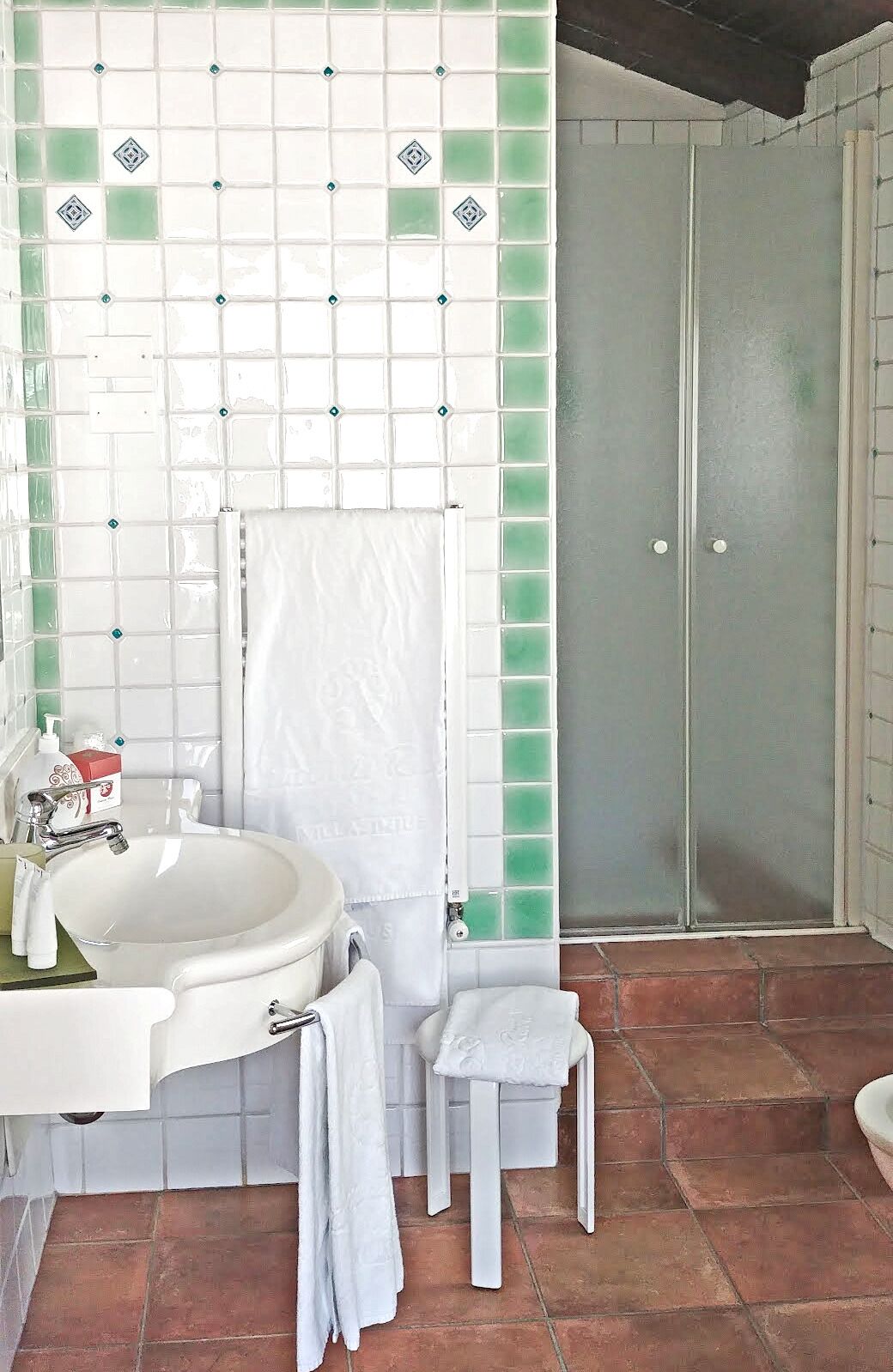 Un baño con un lavamanos blanco, un perchero y una zona de ducha.