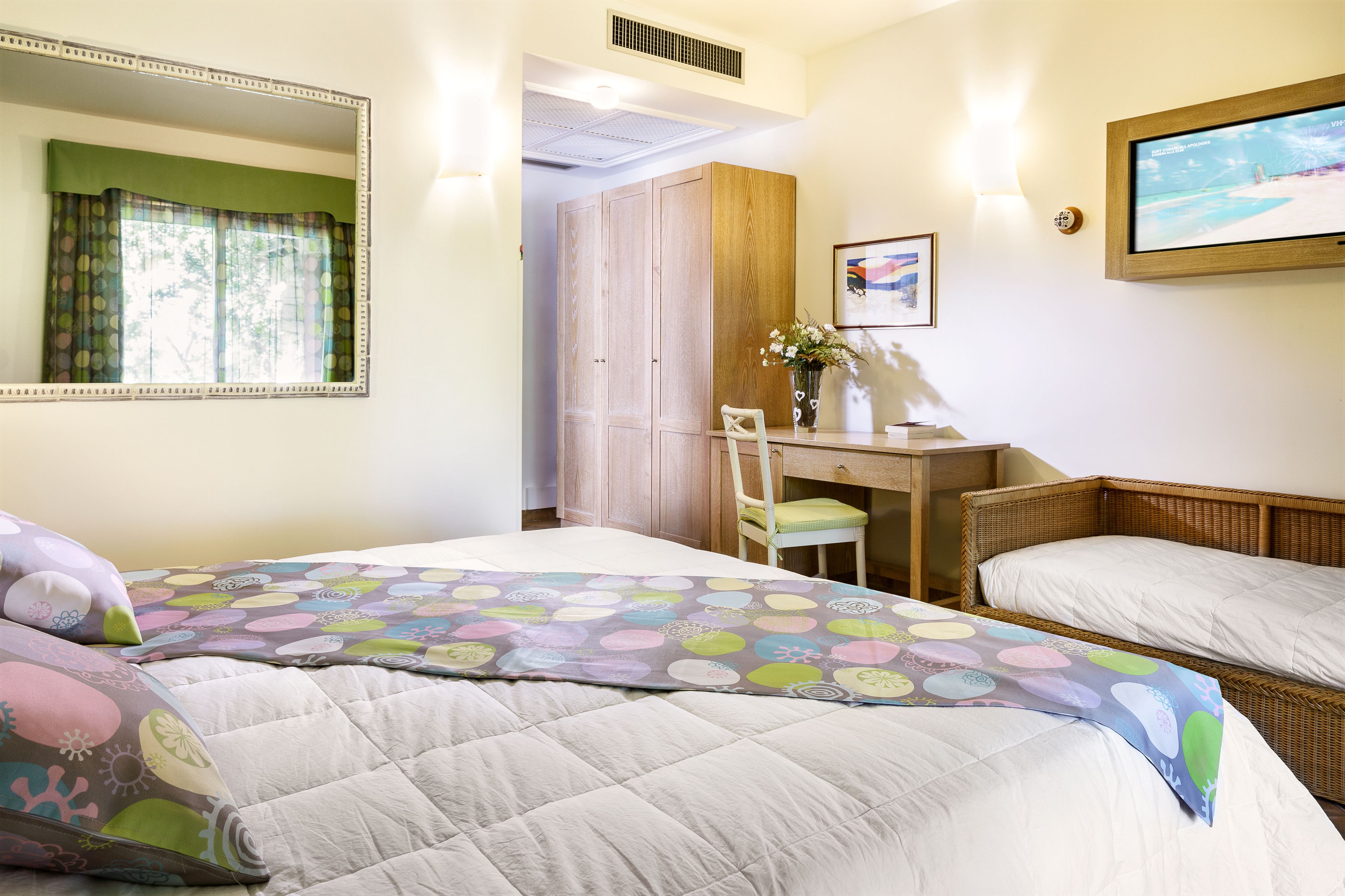 Habitación de hotel con dos camas, un escritorio, una silla y una televisión.
