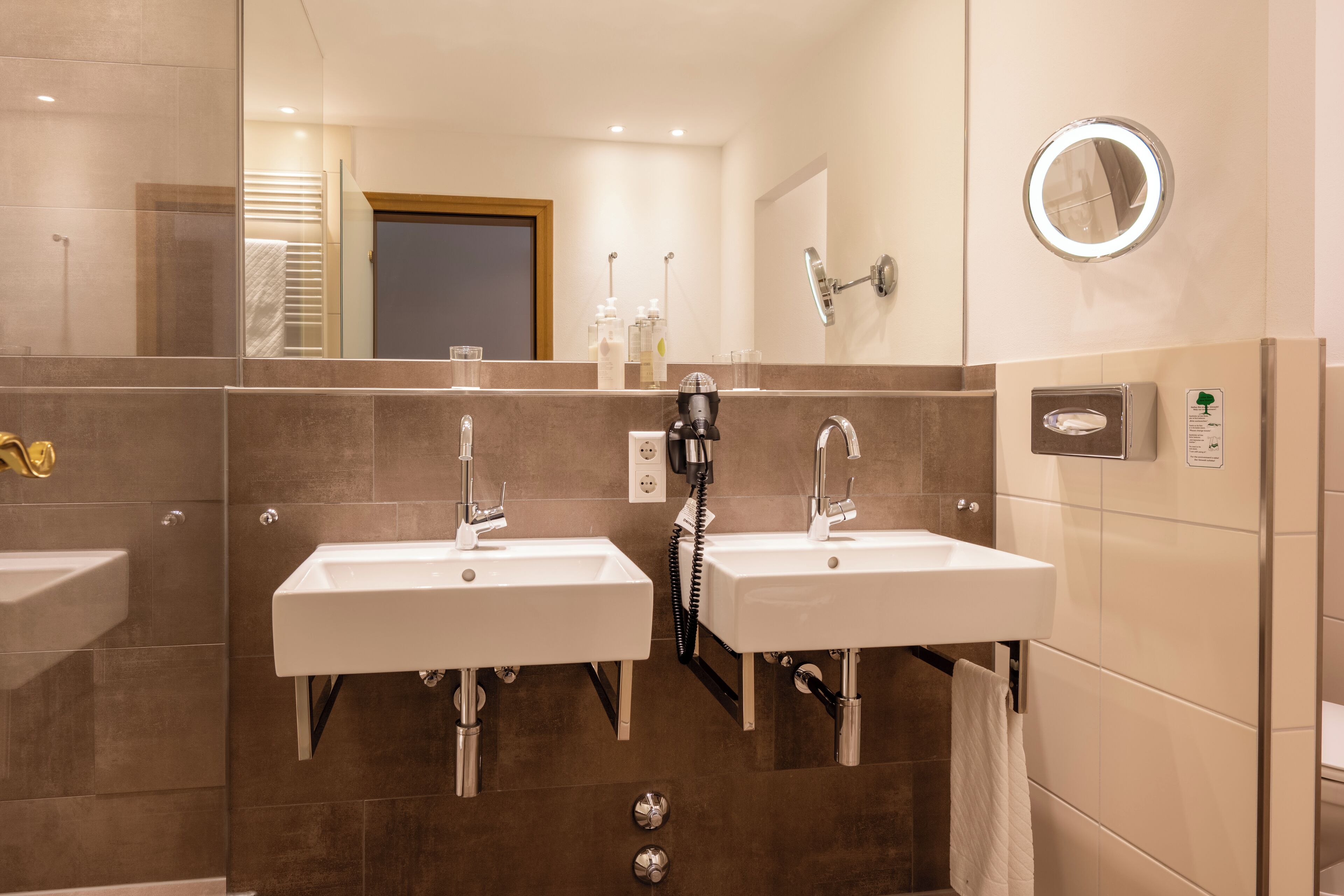 Une salle de bain moderne avec deux lavabos, un miroir et un porte-serviettes.