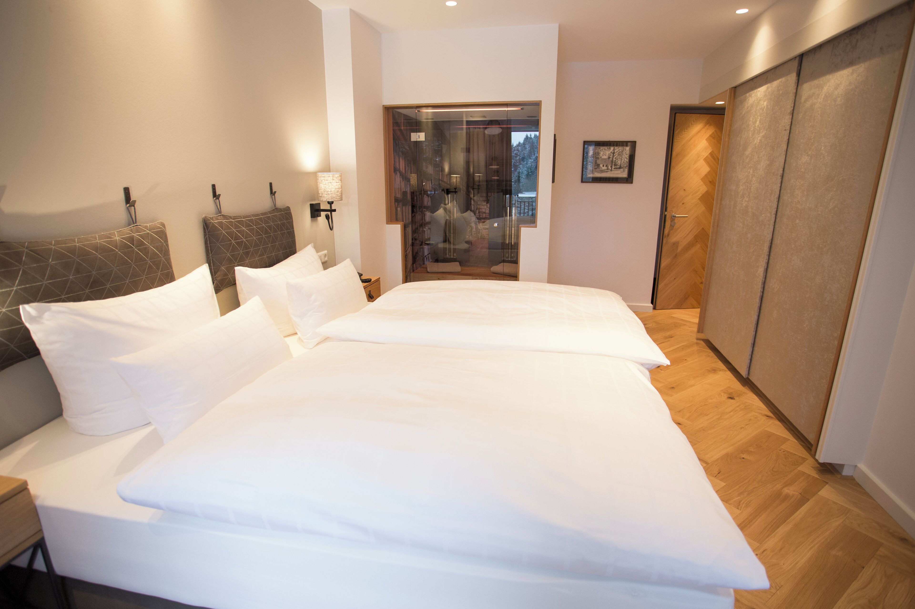 Ein Hotelzimmer mit einem großen Bett, einem Kleiderschrank und einer Glastür, die auf einen Balkon führt.