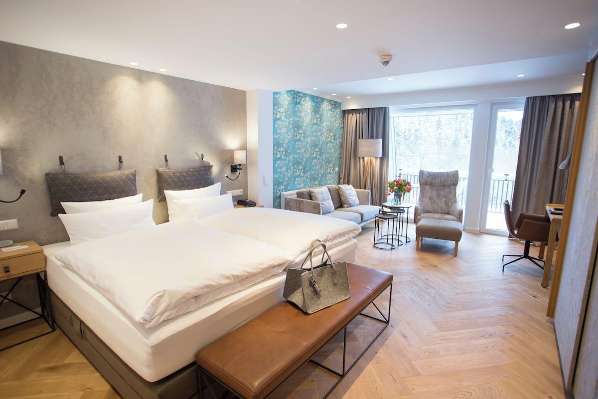 A hotel room with a large bed, a sofa, a chair, and a desk.