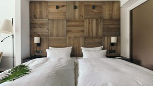 A hotel room with two beds, wooden headboard, bedside lamps, and a radiator. - Hotel Jagdhaus Wiese (Schmallenberg)