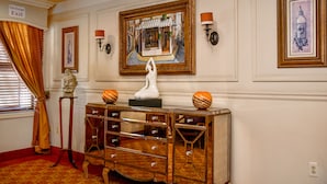 A hotel lobby with a mirrored console table, framed artwork, and a 'Fire Escape Exit' sign. - Brand Plaza Hotel (Glendale)