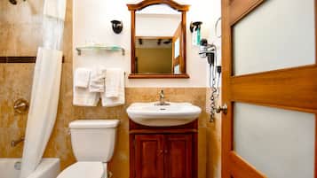 A bathroom with a toilet, sink, mirror, and shower curtain.