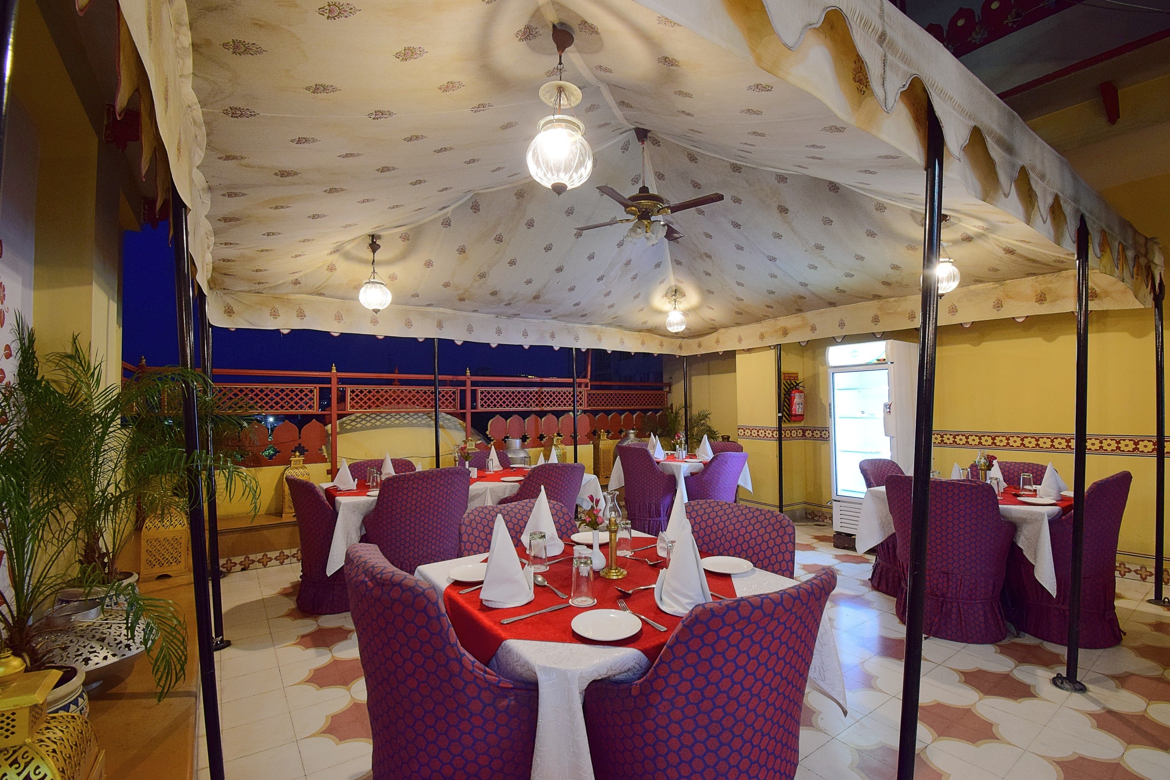 A restaurant with tables set for dining, chairs, and a ceiling fan.