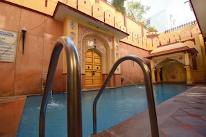 Swimmers can enjoy the pool surrounded by traditional architectural details and decorative elements.