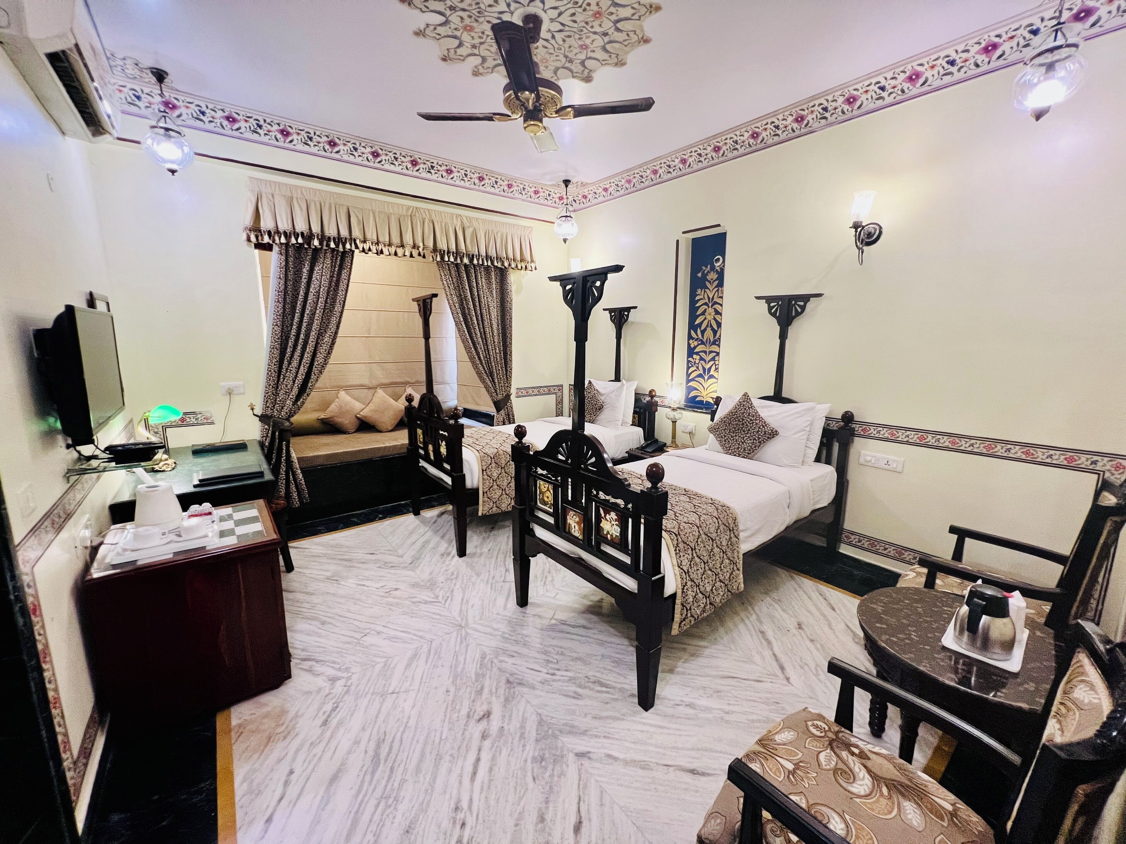 A hotel room with a bed, two bedside tables, a sofa, a desk, and a chair.