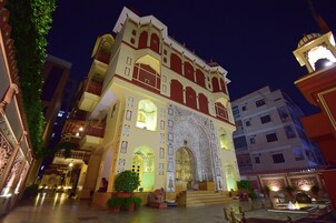Um edifício histórico com arquitetura ornamentada, um pátio central e uma fonte.